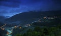 Landscape of hills covered in buildings and forests under a cloudy sky during the night Royalty Free Stock Photo