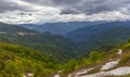 Landscape of hills covered in forests and snow under a dark cloudy sky Royalty Free Stock Photo