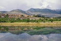 Landscape with hills, mountains and small town on river bank is reflected in water. Bosnia and Herzegovina, Trebisnjica river Royalty Free Stock Photo