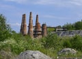 Landscape with huge cone-shaped brick pipes of an abandoned factory among lush greenery with flowers