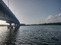 A landscape image of a lake with a bridge and greenery on the other side and glare of sunlight from the left Royalty Free Stock Photo