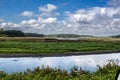 Landscape image of the marsh at Bombay Hook Wildlife Refuge NWR. A blue sky and white puffy clouds on a summer day in August. Royalty Free Stock Photo