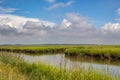 Landscape image of the marsh and grassy islands at Bombay Hook Wildlife Refuge with blue sky and fluffy clouds. Royalty Free Stock Photo