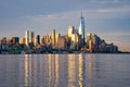 Landscape image of the skyline of Lower Manhattan at sunrise, with reflections seen in the