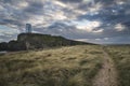 Landscape image of Twr Mawr lighthouse with windy grassy footpath in foreground at sunset