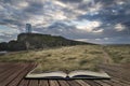 Landscape image of Twr Mawr lighthouse with windy grassy footpath in foreground at sunset concept coming out of pages in book