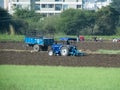 Cultivation, Tractor cultivation in a field and labours in background.