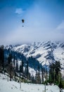 A landscape involving snow capped valley with pine trees and mountains. Paragliding going on Royalty Free Stock Photo