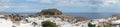 Photo panorama. View of the white buildings of Captains houses and the ancient Acropolis of Lindos in August. Royalty Free Stock Photo