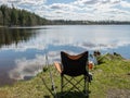 Landscape with a lake and beautiful cloud reflections, fishing accessories on the lake shore Royalty Free Stock Photo