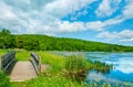 Landscape lake and blue sky. Beautiful wild nature, forest. Lake with small wooden bridge