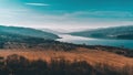 Landscape of a lake next to bare yellow field and mountains in the distant background. Sunny autumn day with blue sky Royalty Free Stock Photo