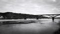 Landscape with a large, multi-span, arched bridge. A black and white photo with a large frozen river and a large bridge over it.