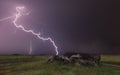 Landscape with lightning striking behind dead tree trunk