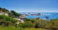 Landscape of many rocks in the ocean surrounded by green bushes or shrubs. Large stones around tidal pool in the sea Royalty Free Stock Photo