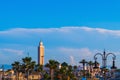 Landscape with minaret of a square shaped mosque on the background of a blue sky, with an approaching big cloud in the