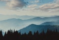 Landscape of misty mountains. View of coniferous forest, layers of mountain and haze in the hills at distance. Beautiful cloudy sk Royalty Free Stock Photo