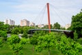Modern red metallic bridge and vivid green grass and trees in Drumul Taberei Park (Parcul Drumul Taberei) also