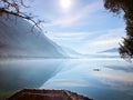 Landscape morning fog, mountains reflected in calm water, man is sailing on a boat Royalty Free Stock Photo