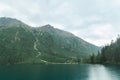 Landscape of a mountain lake with blue water in the rain with a wooden tourist house. Lake Morskie Oko, view of a wooden house. Royalty Free Stock Photo