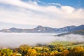 A landscape with mountain surrounded by fog in the autumn season