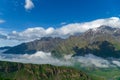 Landscape mountain view peaks in snow and green hills, deep blue sky and huge white clouds background, Caucasian mountains, Kazbek