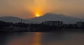 Landscape of mountains and lake during dawn time in the morning sun rising behind the clouds and Tyndall effect on water. Royalty Free Stock Photo