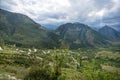 Landscape with mountains, road and fields with trees, flowers on a cloudy summer day after rain with a haze Royalty Free Stock Photo