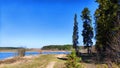 Landscape and nature with calm water of big lake, trees on the shore and blue sky on autumn or spring sunny day. Sun and Royalty Free Stock Photo