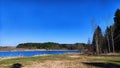 Landscape and nature with calm water of big lake, trees on the shore and blue sky on autumn or spring sunny day. Sun and Royalty Free Stock Photo