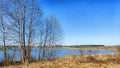 Landscape and nature with calm water of big lake, trees on the shore and blue sky on autumn or spring sunny day. Sun and Royalty Free Stock Photo