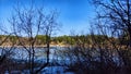 Landscape and nature with calm water of big lake, trees on the shore and blue sky on autumn or spring sunny day. Sun and Royalty Free Stock Photo