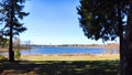 Landscape and nature with calm water of big lake, trees on the shore and blue sky on autumn or spring sunny day. Sun and Royalty Free Stock Photo