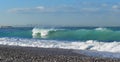 Big wave on pebbles shore with Beirut in a far endLandscape with karst topography and mountain in background,