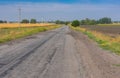Landscape with an old, cracked asphalt road between fields leading to remote village in Poltavskaya oblast, Ukraine Royalty Free Stock Photo