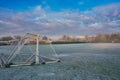 Landscape of an old football field covered in the frost under a blue cloudy sky