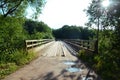 Landscape, old wooden bridge over the river among the trees on a summer sunny day, puddles on a sandy road, Royalty Free Stock Photo