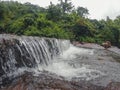 A wide angle photo of a sawatsada waterfall in the middle of a forest in chiplun.