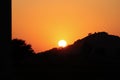 A landscape photo with a bright sun shining brightly from behind a silhouette mountain range and wild silhouette trees.concept to Royalty Free Stock Photo