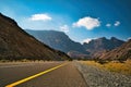A landscape photo of the mountains, clouds, blue sky and large rocks taken from the middle of the road in Oman Royalty Free Stock Photo