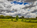 Landscape photo taken on a summer day in the afternoon with a beautiful sky with cirrus clouds, green fields, trees, plants on a Royalty Free Stock Photo