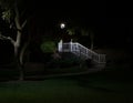 Landscape photo of a white stairwell lit only by a small lamp post in the park at night.