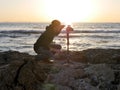 Landscape photography shot with photographer setting up his camera on a beach at sunset. Royalty Free Stock Photo