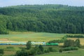 Landscape with a railway line, train, hills and fo