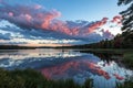 Landscape with red clouds on the blue sky over the lake seen in the mirror. Mirror image of clouds in the shape of a circle in the Royalty Free Stock Photo