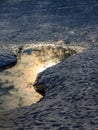 Landscape reflection of the setting sun in the ice hole on a snowy ice lake Royalty Free Stock Photo