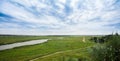 Landscape river in a bright green summer field on a cloudy day Royalty Free Stock Photo