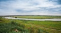 Landscape river in a bright green summer field on a cloudy day Royalty Free Stock Photo