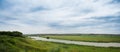 Landscape river in a bright green summer field on a cloudy day Royalty Free Stock Photo