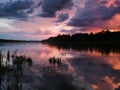 Landscape with river, clouds, water grass and mountain in distance at sunset. Dramatic riverine scene during cloudy dusk with last Royalty Free Stock Photo